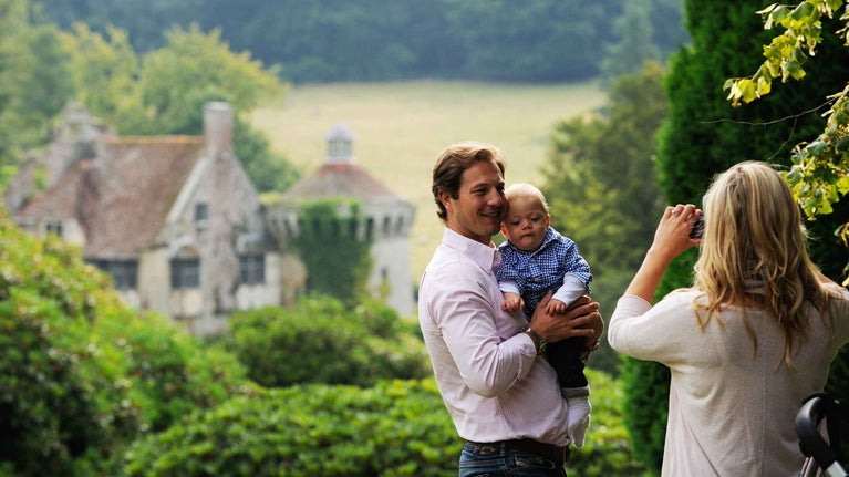 A family photo being taken in the garden at Scotney Castle, Kent with the ruined castle in the background